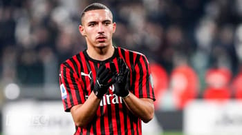Joueur de football en maillot rouge et noir sur le terrain.