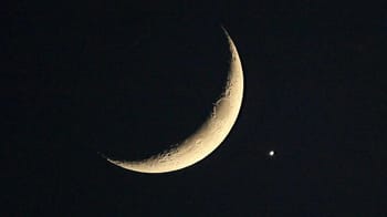 Ciel nocturne avec lune croissante et étoile brillante.