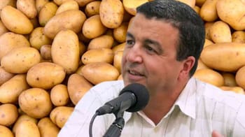 Homme parlant à un micro avec des pommes de terre en arrière-plan.