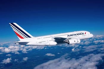Avion Air France survolant les nuages dans un ciel bleu clair.