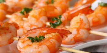Crevettes sur brochette avec herbes fraîches, vue rapprochée.