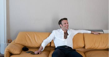 Homme souriant assis détendu sur un canapé en cuir beige.