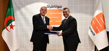Deux hommes en costume se serrent la main lors d'une signature officielle.