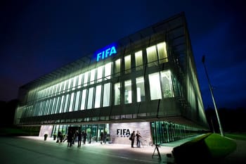 Bâtiment moderne de la FIFA illuminé la nuit avec des visiteurs devant.