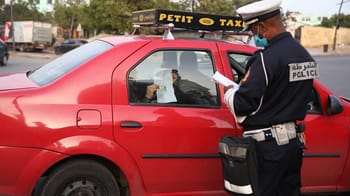 Policier vérifiant un taxi dans une rue marocaine.