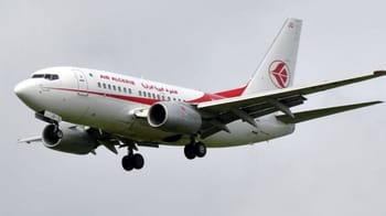 Avion de ligne blanc et rouge en vol dans un ciel nuageux.