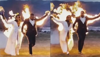 Deux mariées marchent avec un homme sur la plage en feu.