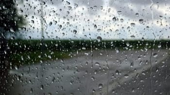 Fenêtre embuée avec pluie et orages visibles à l'extérieur.