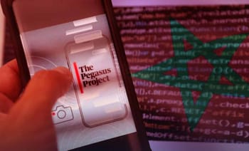 Smartphone affichant le logo de Pegasus avec code informatique en arrière-plan.