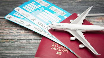 Billets d'avion, passeport et modèle d'avion sur une table en bois.