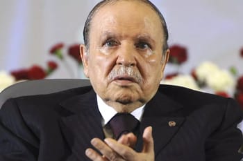 Portrait d'un homme politique algérien en costume sombre lors d'une conférence.