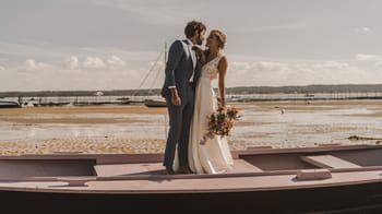 Jeune couple en robe de mariage sur un bateau au bord de l'eau.