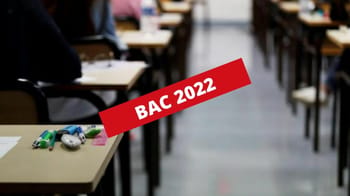 Salle d'examen du Bac 2022 avec des élèves et des bureaux.