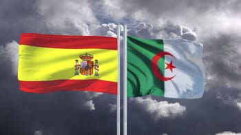 Drapeaux de l'Espagne et de l'Algérie flottant dans le ciel nuageux.