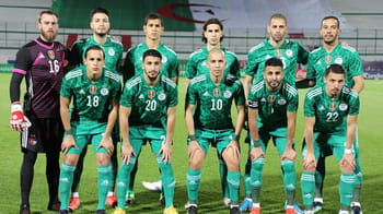 Groupe de joueurs de football algériens en tenue verte sur le terrain.