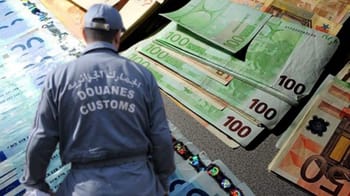 Contrôleur des douanes inspectant des billets de banque en devises.
