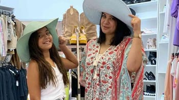 Deux femmes souriantes portant de grands chapeaux dans un magasin de vêtements.