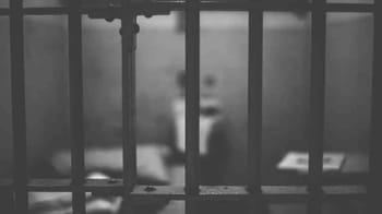 Cellule de prison avec barreaux en France, image en noir et blanc.