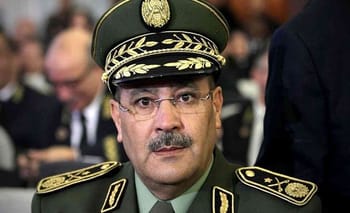 Homme en uniforme militaire avec chapeau et lunettes, portrait sérieux.