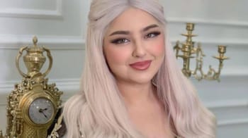 Jeune femme souriante aux cheveux longs et blonds dans un décor élégant.
