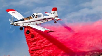 Avion de lutte contre l'incendie déversant du retardant rouge sur un feu de forêt.