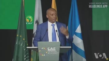 Patrice Motsepe lors d'une conférence en Algérie avec drapeaux africains en arrière-plan.