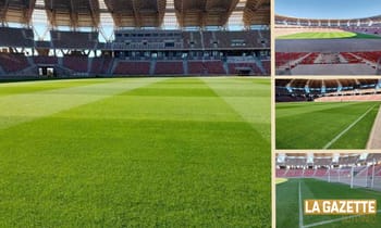 Stade de football vide avec pelouse verte et tribunes.