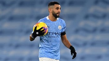 Mahrez en entraînement, portant un maillot de Manchester City et tenant un ballon de football.