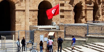 Amphithéâtre antique en Tunisie avec touristes et drapeau tunisien.