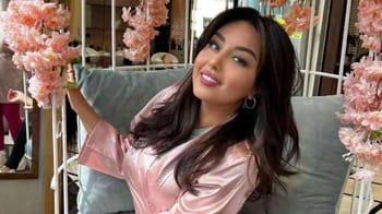 Yasmine Belkacem souriante dans un cadre floral élégant.