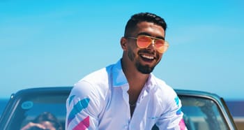 Homme souriant avec lunettes de soleil en voiture sous le soleil.