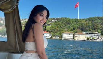 Yasmine Belkacem souriante en bateau avec vue sur la mer et la ville.