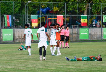 Joueurs de football en action lors des Jeux islamiques avec drapeaux africains en arrière-plan.