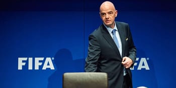 Homme en costume devant un fond FIFA, lors d'une conférence officielle.