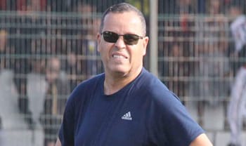 Entraîneur de football portant lunettes et t-shirt bleu.
