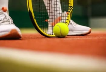 Raquette et balle de tennis sur le court en intérieur.