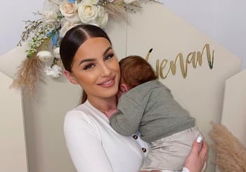 Kamila avec son bébé lors d'un événement, sourire et tendresse.
