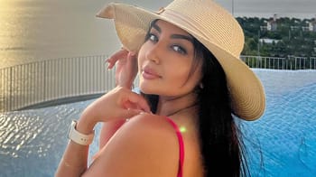 Femme portant un chapeau de soleil et un maillot rouge près de la piscine.