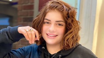 Jeune femme avec cheveux bouclés, souriante, portant un sweat noir.