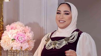 Maya Redjil souriante portant un hijab et une robe élégante.