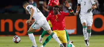 Joueur algérien en action contre un adversaire guinéen lors du match.