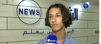 Jeune homme parlant à la caméra lors d'une interview télévisée.
