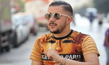 Homme portant des lunettes de soleil et t-shirt à motif urbain.