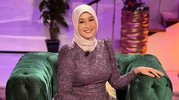 Maya Redjil souriante en tenue élégante lors d'une interview.