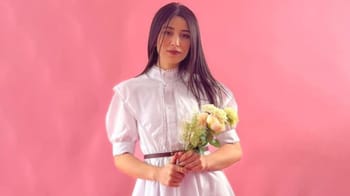 Femme avec bouquet de fleurs, portrait sur fond rose.