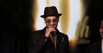 Soolking avec un chapeau et des lunettes lors d'une cérémonie de récompense.
