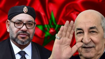 Deux hommes en costume avec drapeau marocain en arrière-plan.