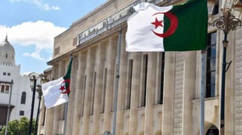 Drapeaux algériens flottant devant un bâtiment officiel en Algérie.