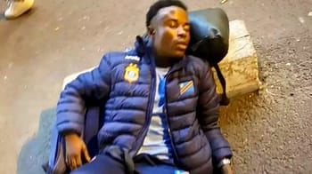 Jeune homme endormi avec sac à dos sur un banc en extérieur.