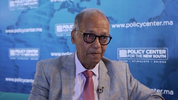 Abdelhak Bassou en discussion, portant un costume et des lunettes.